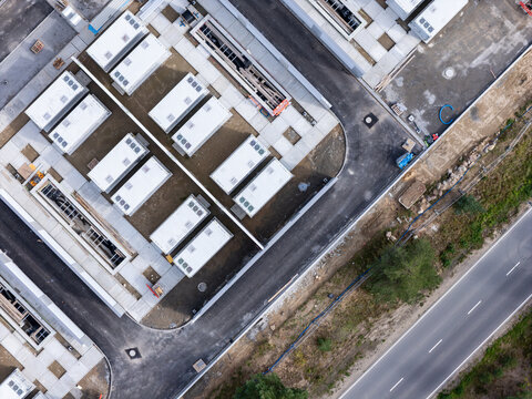 Aerial view of a construction site featuring rows of white modular units, paved walkways, and an adjacent asphalt road in Poland.