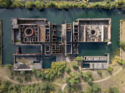 Aerial view of the abandoned foundations of the unfinished Zarnowiec nuclear power plant, surrounded by water and greenery in Zarnowiec, Poland.