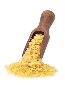 Millet flakes spilling from wooden scoop, pile of flakes, isolated on white background
