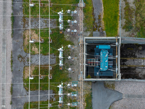 Aerial view of an electrical substation with high-voltage equipment, transformers, and power lines set within a fenced industrial area in Andalsnes, More og Romsdal, Norway.