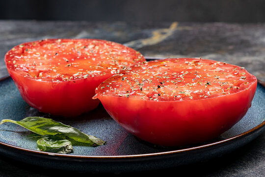 Close-up of juicy tomato halves with herbs on a blue plate