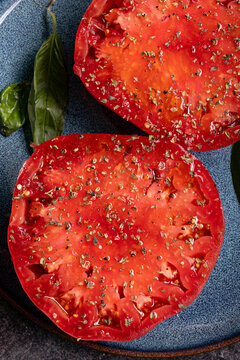 Vertical overhead close-up of tomato halves with herbs and basil