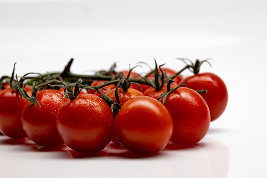 Cherry tomatoes on the vine with water droplets on white
