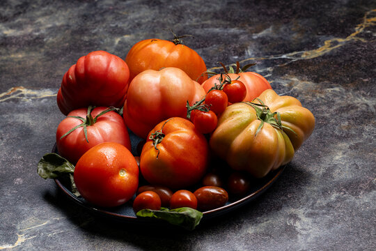 Assorted colorful tomatoes on a plate on a dark stone surface