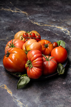 Assorted tomatoes on a plate with vertical copy space on dark stone