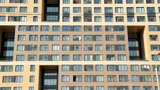 A modern apartment building stands tall in a residential neighborhood of Saint Petersburg. Many windows catch the gentle daylight in neat rows.