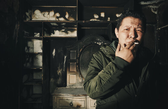 Man smoking cigarette inside damaged fire-ravaged room
