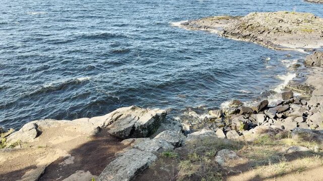 Waves ripple across the water against rocky shores. This tranquil scenery creates a peaceful and calm mood on Valaam, Lake Ladoga.