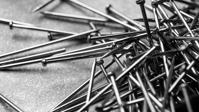 Macro close up pile of metallic straight pins black and white background.