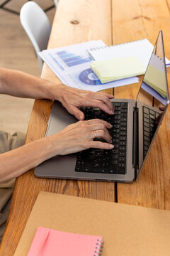 Mature woman work on laptop at wooden office desk