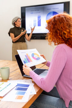 Business colleagues review financial charts during office meeting