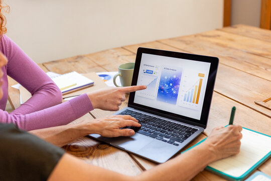 Two-generation women review business data on laptop