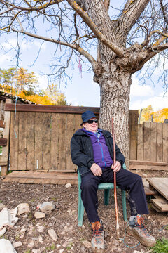 Elderly farmer resting beneath a leafless backyard tree