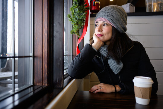 Thoughtful woman by cafe window in winter at Sylvan Lake