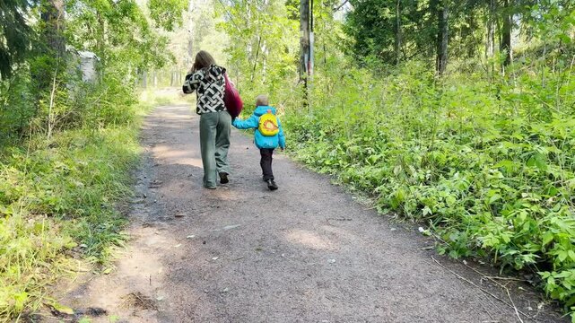 A woman and child walk along a forest path in Valaam, Lake Ladoga. This green wooded trail inspires a calm, happy feeling of peaceful exploration.