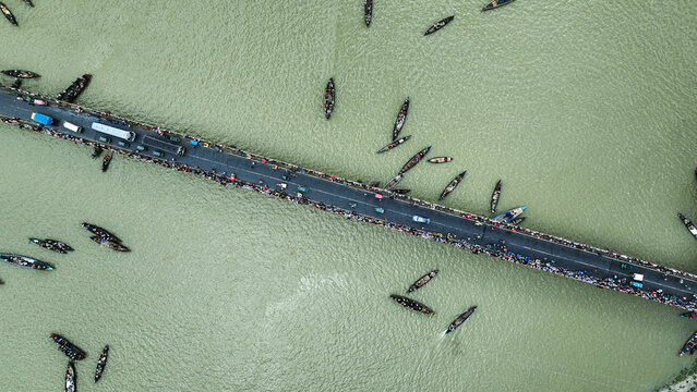 Baghabari, Rajshahi Division, Bangladesh - 20 August 2022: Aerial view of the Baghabari bridge crossing the river, surrounded by numerous small wooden boats and people navigating the water.