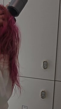 Drying hair with a hair dryer in a bathroom after washing it
