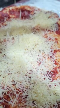 Cheese is added to pizza before baking in a kitchen