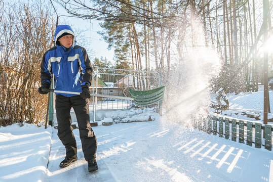 Man shoveling snow in a sunny winter yard