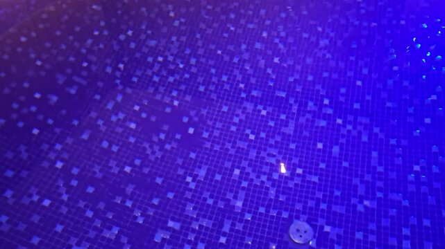 Water reflects light in a pool with tiles showing different patterns in blue hues over time