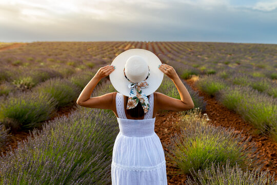 Woman in lavender field wearing white dress and sunhat