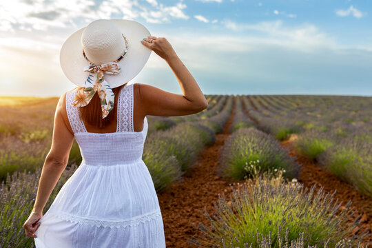 Woman in lavender field at sunset wearing a sunhat