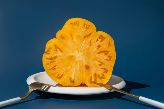 Yellow tomato slice on plate with fork and knife
