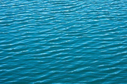Turquoise water surface with gentle wave pattern texture