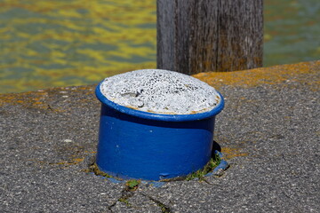 Obraz premium Blue bollard with weathered white top on a dock by the water