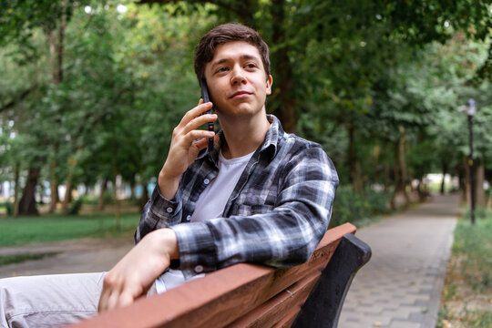Young man talk on smartphone while sit in park