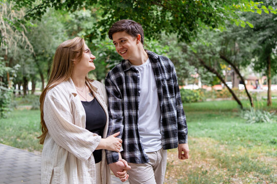 Young couple hold hands during romantic walk in park