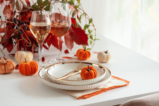 Elegant Thanksgiving Table Setting with Pumpkins Wine Glasses and Autumn Leaves