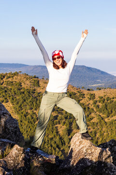 Happy hiker raise arm on mountain summit at sunset