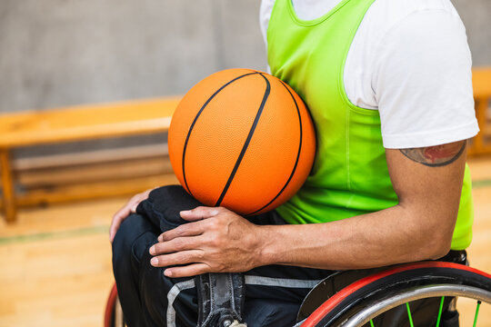 Athlete holding basketball while sitting in wheelchair on court