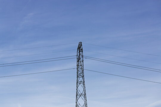Tall electricity pylon against a clear blue sky with power lines stretching across