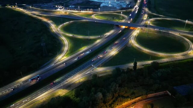 Highway Interchange at Night: An aerial view captures the intricate design of a highway interchange illuminated by the glow of streetlights and vehicle headlights.
