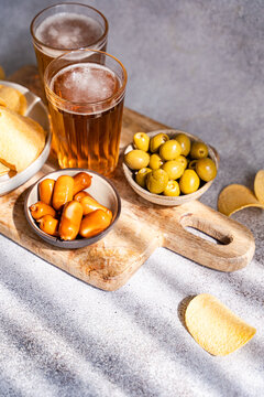 Beer, snack, olive and sausage on wooden cutting board
