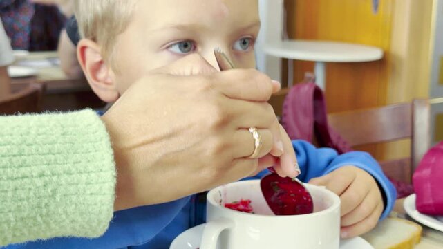 A cute boy eats soup from a bowl on a cruise ship on Lake Ladoga. This heartwarming moment evokes a happy, peaceful, and loving feeling.