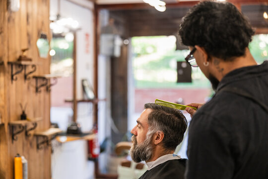 Barber combing client's hair in barbershop