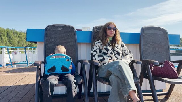 A woman and boy relax on deck chairs on a cruise ship at Valaam, Lake Ladoga. This cozy moment evokes a happy, peaceful, and joyful feeling.
