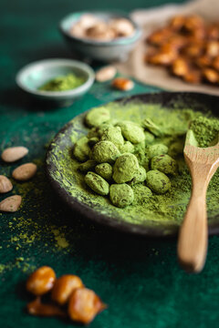 Matcha tea coated almonds with wooden spoon and powder