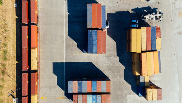 Indjija, Serbia - 24 August 2026: Aerial view of shipping containers stacked in a logistics yard with long shadows cast on the concrete ground.