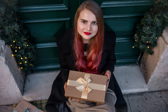Woman with Christmas gift at decorated front door
