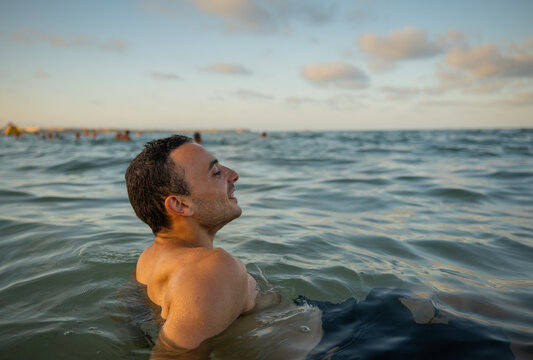 Man relax in ocean water at sunset near beach