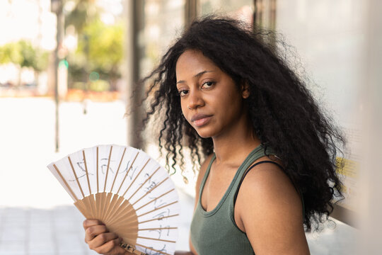 Woman cools off with handheld fan outdoors in summer