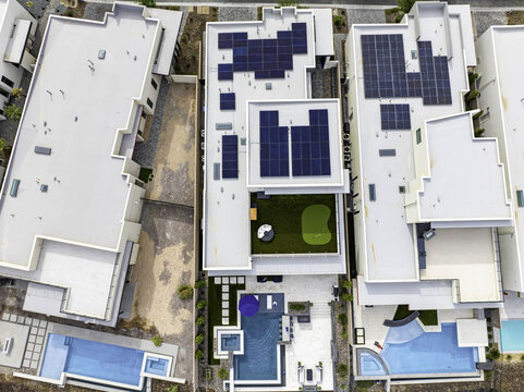 Los Angeles, California, United States - 13 October 2023: Aerial view of modern homes with rooftop solar panels, a private putting green, and swimming pools in a suburban neighborhood.