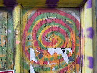 Detailed close-up distressed pink, orange, teal peeling spiral graffiti street art door frame   © LilliM