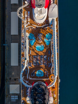 Nassau, The Bahamas - 27 December 2025: Aerial view of Nassau Cruise Port featuring the top deck of a cruise ship with swimming pools, water slides, and lounge chairs.