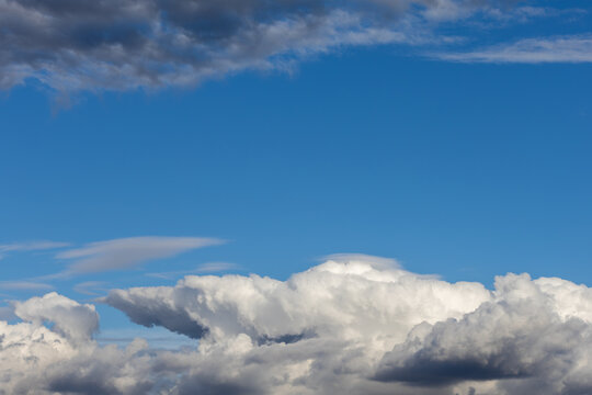 A view of the atmosphere showing blue sky framed by a dark cloud above and a white cumulus cloud below