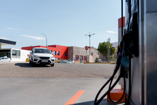 White car approach gasoline pump at urban gas station